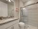 Bathroom featuring a granite countertop, white cabinets and tiled shower with a sliding glass door at 13731 Vadini St, Venice, FL 34293