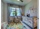 Bedroom featuring a crib, cozy chair, neutral curtains, and decor with jungle-themed elements at 13731 Vadini St, Venice, FL 34293