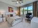 Bright bedroom with large window, ceiling fan, and modern white furniture with art on the wall at 13731 Vadini St, Venice, FL 34293