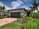 Charming home featuring a two-car garage, lush landscaping and a brick driveway at 13731 Vadini St, Venice, FL 34293