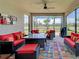 Screened lanai with stylish wicker furniture, vibrant pillows, and views of a serene lake and palm trees at 13731 Vadini St, Venice, FL 34293