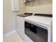 Bright laundry room featuring a white Whirlpool washer and dryer with tile flooring and upper storage shelving at 13731 Vadini St, Venice, FL 34293
