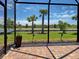 Screened-in patio with brick pavers, offering tranquil views of the lush lawn, palm trees, and serene water at 13731 Vadini St, Venice, FL 34293