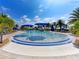 Beautiful community pool with blue umbrellas and lounge chairs, surrounded by lush landscaping and palm trees at 13731 Vadini St, Venice, FL 34293