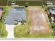 An aerial view of the property, including the home, pool, dock, waterfront, and an adjacent vacant lot at 15448 Avery Rd, Port Charlotte, FL 33981