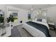 Cozy bedroom with a plush bed, soft lighting, and view to the landscaped yard through large windows at 15448 Avery Rd, Port Charlotte, FL 33981