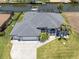 An aerial view of a home's facade, showing a well-manicured lawn, palm trees, three-car garage, and waterfront location at 15448 Avery Rd, Port Charlotte, FL 33981