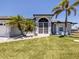 A charming home exterior showcasing arched windows, a well-kept lawn, and beautiful palm trees at 15448 Avery Rd, Port Charlotte, FL 33981