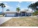 Charming single-story home with a white tile roof, well-maintained lawn and swaying palm trees at 1568 Ringtail Rd, Venice, FL 34293