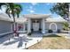 Inviting front entrance with double doors, bright flowers, swaying palm tree, and white gravel at 1568 Ringtail Rd, Venice, FL 34293