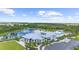 Aerial view of a luxurious community clubhouse, pool, and surrounding natural landscape with a picturesque pond and fountain at 18001 Grand Prosperity Dr, Venice, FL 34293