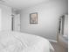 Clean bedroom with white bedding, framed artwork, mirror and door leading to the laundry room at 18001 Grand Prosperity Dr, Venice, FL 34293