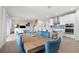 Open-concept dining area with a wood table, tufted blue chairs, seamlessly connecting the living room and kitchen at 18001 Grand Prosperity Dr, Venice, FL 34293