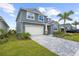 Two-story home with a brick-paved driveway leading to a two-car garage, complemented by a well-maintained lawn and landscaping at 18001 Grand Prosperity Dr, Venice, FL 34293