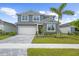 Charming two-story home featuring a gray facade, well-manicured lawn, and a brick-paved driveway leading to a two-car garage at 18001 Grand Prosperity Dr, Venice, FL 34293