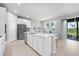 Modern kitchen boasts stainless steel appliances, white cabinets, an island with seating, and sliding glass doors at 18001 Grand Prosperity Dr, Venice, FL 34293