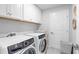 Laundry room with white washer and dryer, white cabinets, and a laundry basket at 18001 Grand Prosperity Dr, Venice, FL 34293