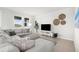 Bright living room features a comfy grey sectional sofa, decorative pillows, and an entertainment center with mounted TV at 18001 Grand Prosperity Dr, Venice, FL 34293