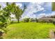 Expansive backyard featuring lush green grass, mature landscaping, and a partial view of a pool at 2000 Jasmine Way, North Port, FL 34287