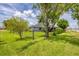 Lush green backyard featuring mature shade trees, black chain-link fence, and manicured landscaping at 2000 Jasmine Way, North Port, FL 34287