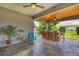 Relaxing covered patio with ceiling fans, a built-in bar, and a charming turquoise chair surrounded by greenery at 2000 Jasmine Way, North Port, FL 34287
