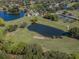 Aerial view showcasing a golf course with a water hazard, clubhouse, and tennis courts at 2022 Calusa Lakes Blvd, Nokomis, FL 34275