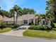 Charming home with a brick driveway and well-manicured landscaping, featuring palm trees and a tile roof at 2022 Calusa Lakes Blvd, Nokomis, FL 34275