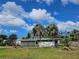 Charming home with palm trees and a hammock, set against a bright blue, partly cloudy sky at 205 Jessica N St, Nokomis, FL 34275