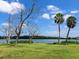 Scenic backyard view featuring a waterfront, well-maintained lawn, and mature palm trees at 214 Pompano Ln, Nokomis, FL 34275