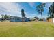 Exterior back view shows the house and its wide grassy lot with other houses nearby at 2980 Siesta Dr, Venice, FL 34293