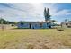 Back exterior view showing house with small covered porch and wide grassy yard at 2980 Siesta Dr, Venice, FL 34293