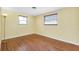 A bright bedroom features hardwood floors, pale yellow walls, and two windows at 2980 Siesta Dr, Venice, FL 34293
