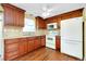 Kitchen with wooden cabinetry, white appliances and hardwood floor at 2980 Siesta Dr, Venice, FL 34293