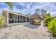 This backyard has white gravel, a screened in porch, and a tiki hut with a picnic table at 307 Bucknell Rd, Venice, FL 34293