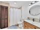Bathroom with tiled shower, wood vanity and cabinet, and round mirror at 307 Bucknell Rd, Venice, FL 34293