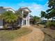 Charming home featuring large windows, a stone walkway, and meticulously maintained landscaping with palm trees at 318 Oakwood Cir, Englewood, FL 34223