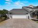 Attached two-car garage featuring a paved driveway, adjacent to palm trees and garden space at 318 Oakwood Cir, Englewood, FL 34223