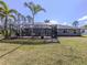 This backyard features a screened in lanai, palm trees and a large green lawn at 3255 Tally Ho Rd # 1, North Port, FL 34291