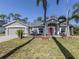 Charming single-story home with a gray exterior, well-manicured lawn, and vibrant pink front door at 3255 Tally Ho Rd # 1, North Port, FL 34291