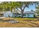 Charming single-story home with a light blue exterior, a palm tree, and mature trees offering ample shade at 421 Blackburn Rd, Nokomis, FL 34275