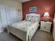 Bedroom features bed with floral pattern bedding and red accent wall at 4213 Vicenza Dr # A2, Venice, FL 34293