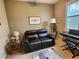 Comfortable room with a leather sofa, piano, and shuttered window, perfect for relaxation at 4213 Vicenza Dr # A2, Venice, FL 34293