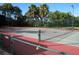 Close up of community tennis court with red and green surface surrounded by a green chain link fence at 4213 Vicenza Dr # A2, Venice, FL 34293