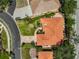 Aerial view showcasing the red tile roof, lush landscaping, driveway, and surrounding neighborhood at 4856 Jacaranda Heights Dr, Venice, FL 34293