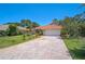 Inviting single-story home with a terracotta roof, lush landscaping, brick driveway, and well-maintained lawn at 4856 Jacaranda Heights Dr, Venice, FL 34293