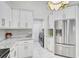 Bright kitchen featuring white cabinets, granite countertops, stainless steel appliances, and a convenient laundry area at 4856 Jacaranda Heights Dr, Venice, FL 34293