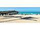 Scenic beach scene with palm tree shadows, people relaxing, and a pier extending into the ocean at 5856 Semolino St, Nokomis, FL 34275