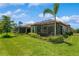 Exterior elevation of a home with a red tile roof, screened lanai, and landscaped backyard at 5856 Semolino St, Nokomis, FL 34275