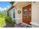 Elegant front entrance features a red door with glass inserts, a welcome mat, and manicured landscaping at 5856 Semolino St, Nokomis, FL 34275