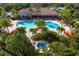A beautiful community pool and hot tub are accompanied by lounge chairs, mature trees, and tropical landscaping at 5856 Semolino St, Nokomis, FL 34275